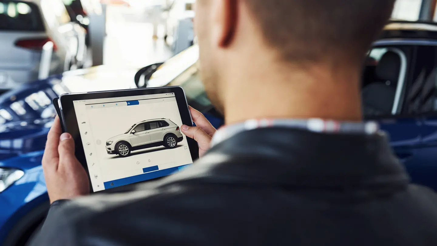 Autoankäufer bewertet Fahrzeug am Tablet