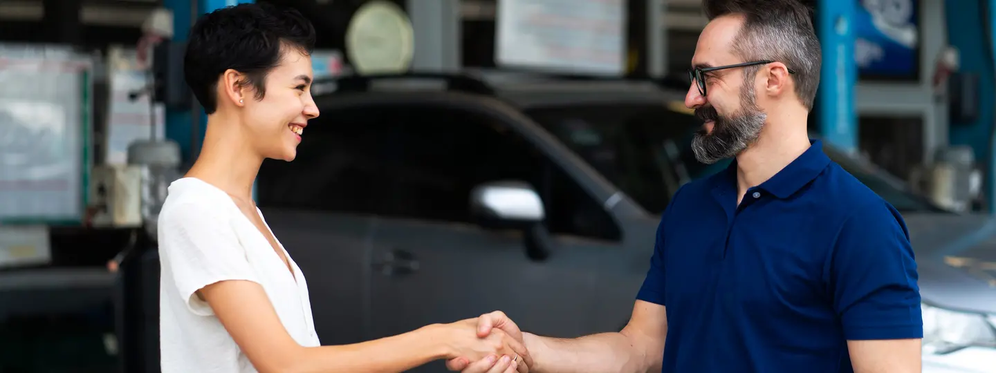 Autohändler und junge Frau einigen sich auf Autoankauf