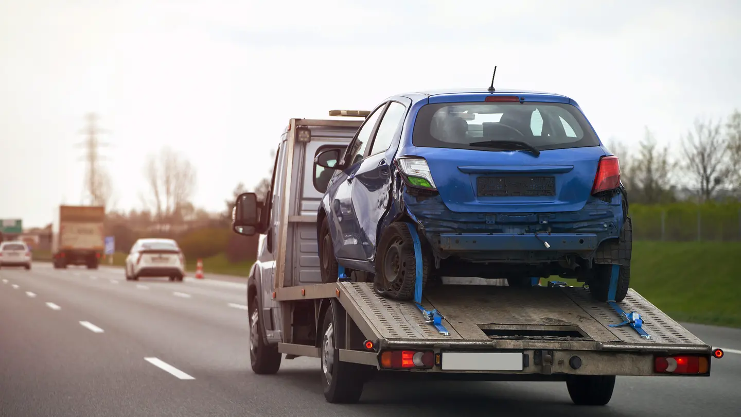 Blaues Abschleppwagen mit Unfallfahrzeug auf Autobahn