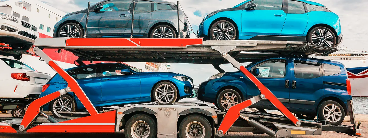 Fahrzeugtransporter fährt mit Gebrauchtwagen in den Exporthafen